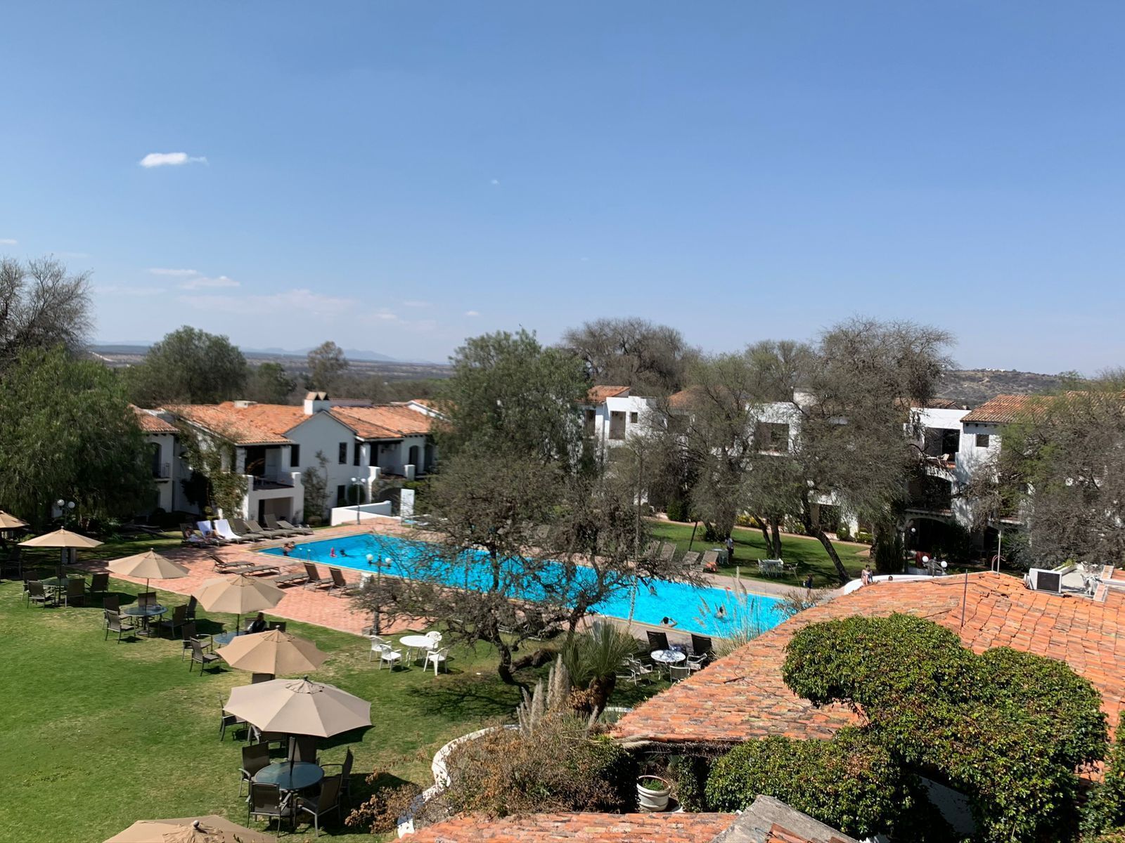 A resort with a swimming pool, outdoor seating, and a view of the surrounding landscape.