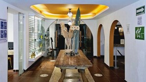 Een hal met een houten tafel, een kroonluchter en een glazen vitrine.