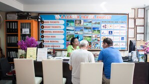 A travel agency office with a counter displaying services like bus tickets, boat tickets, hotel booking, visa run, car rental, and taxi service. - At Phuket Inn Patong Beach (Patong)