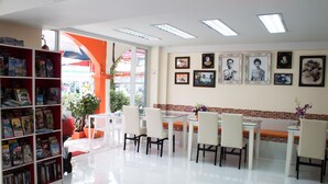 A well-lit, modern interior with a dining area, bookshelves, and framed pictures on the walls. - At Phuket Inn Patong Beach (Patong)