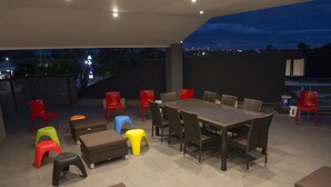 An outdoor patio with a dining table and chairs, surrounded by colorful stools and benches. - Sydney Student Living - Hostel (Concord)