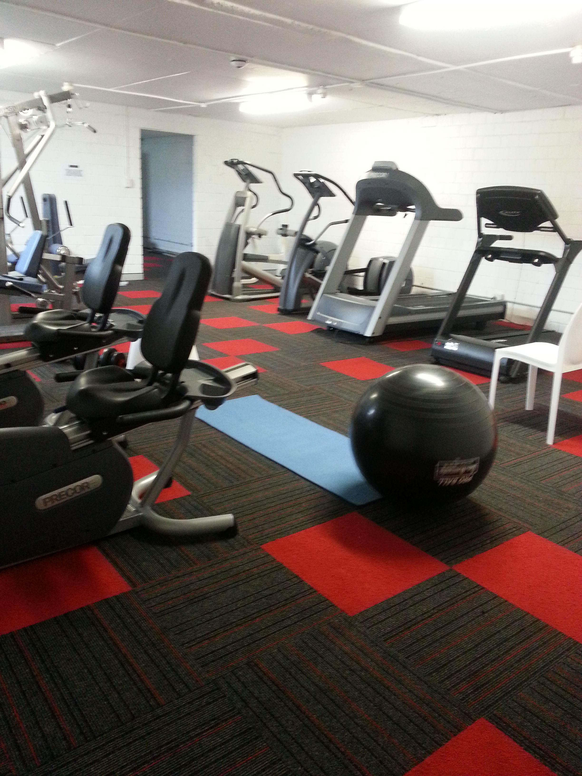 A gym with various exercise equipment including treadmills, elliptical machines, and weight machines.