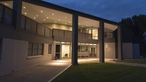 A modern two-story building with a flat roof, large windows, and a covered outdoor area with a staircase leading to the upper floor. - Sydney Student Living - Hostel (Concord)