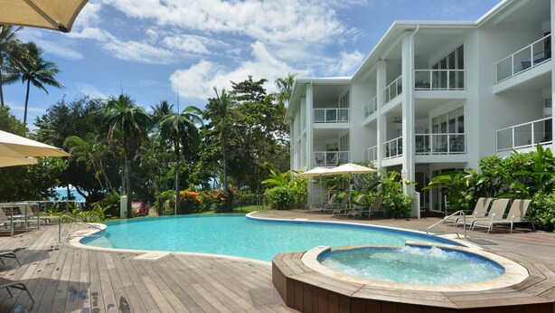 A pool area with a hot tub, lounge chairs, and a wooden deck. - Seascape Holidays- Beaches (Port Douglas)