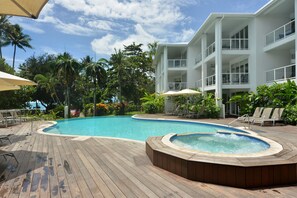 Ein Poolbereich mit Whirlpool, Liegestühlen und einer Holzterrasse.