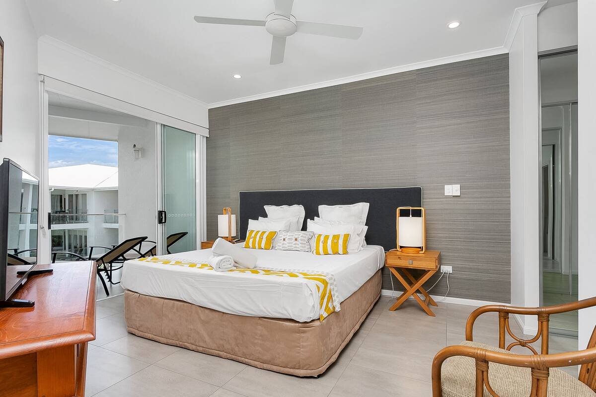 A modern hotel room with a large bed, a desk, and a chair.