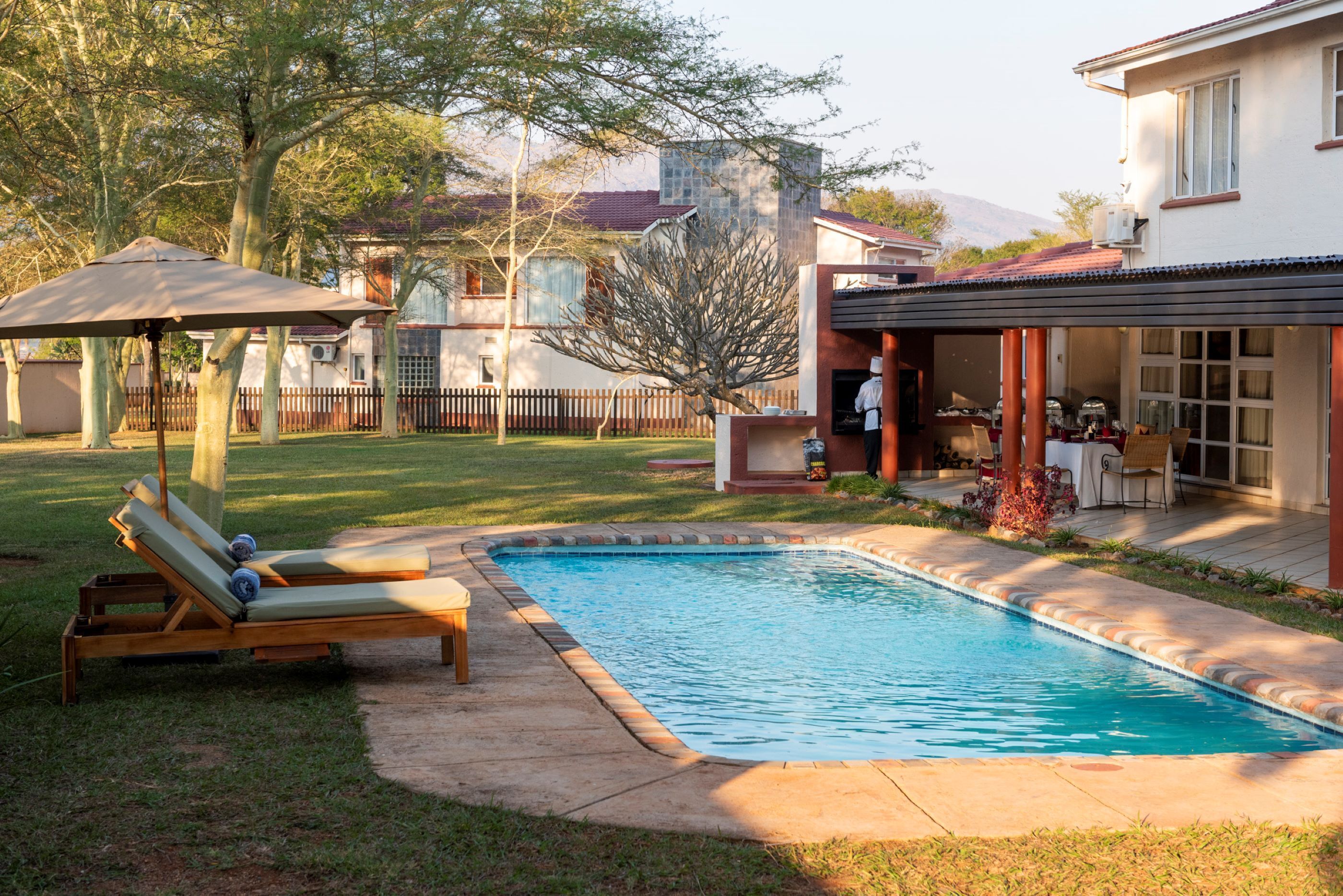 A swimming pool with a sun lounger and a covered patio area.
