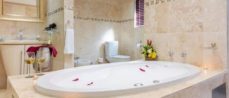 A modern bathroom with a large bathtub, a sink, and a toilet.