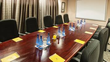 A conference room with a long table, six chairs, and a projector screen.