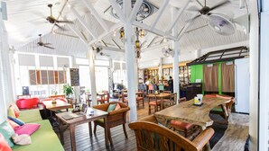 A spacious indoor area with wooden tables and chairs, a bar area, and a seating area with cushions. - Elysia Boutique Resort (Koh Samui)