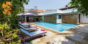 Una piscina al aire libre, sombrillas, sillones reclinables de piscina