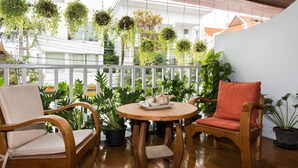 A wooden deck with two chairs and a table, surrounded by potted plants and hanging greenery. - Elysia Boutique Resort (Koh Samui)