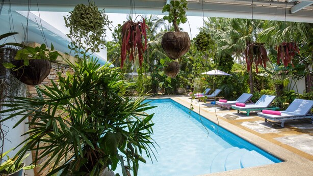 An indoor swimming pool with lounge chairs and hanging planters. - Elysia Boutique Resort (Koh Samui)