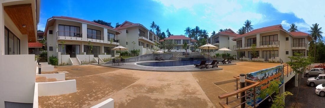 A resort with multiple buildings, a central pool, and outdoor seating areas.