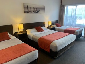 Minibar, escritorio, cortinas blackout y tabla de planchar con plancha