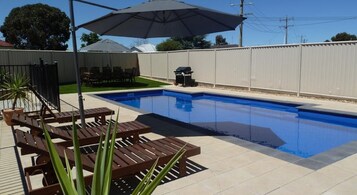 Una piscina al aire libre, sombrillas, tumbonas