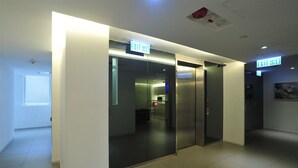 A modern elevator area with glass doors and exit signs. - 60 West Hotel (Hong Kong)