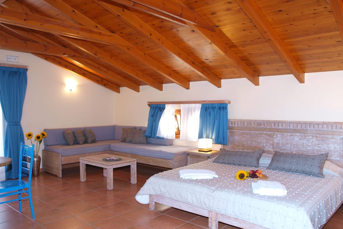 Una habitación acogedora con techo de madera, un sofá, una cama y una mesita.
