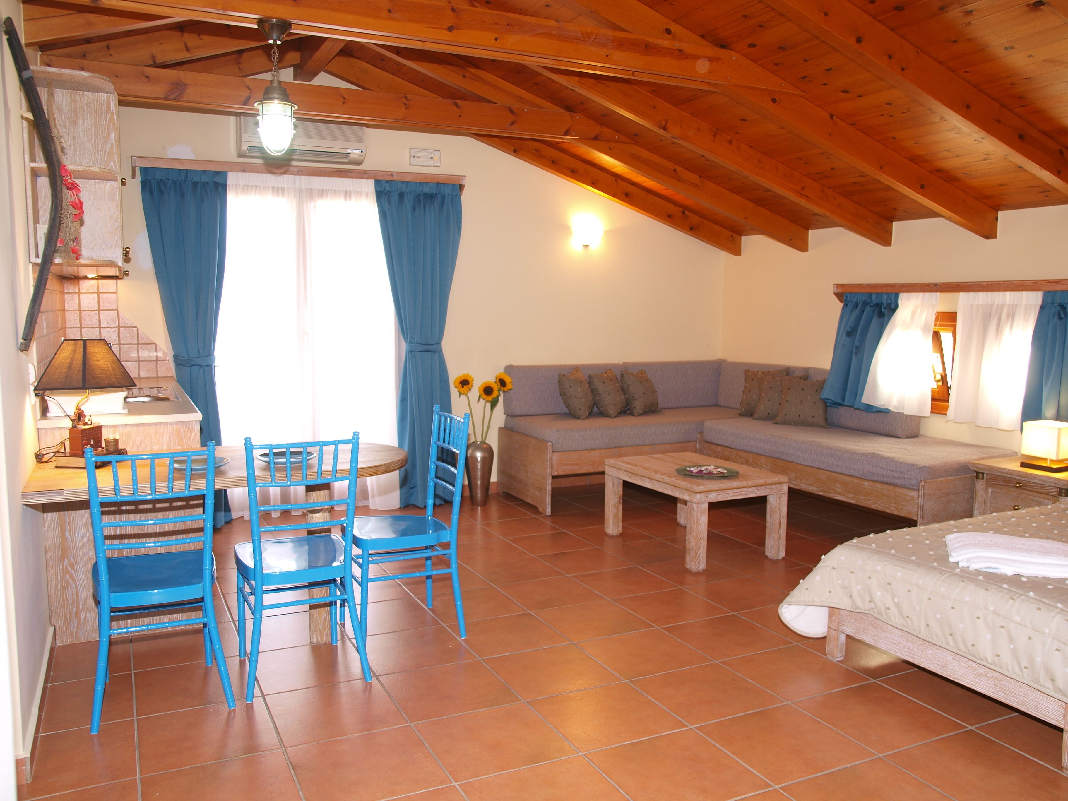 Una habitación acogedora con techo de madera, un sofá, una mesa de comedor con sillas y una cama.