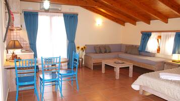Una habitación acogedora con techo de madera, un sofá, una mesa de comedor con sillas y una cama.