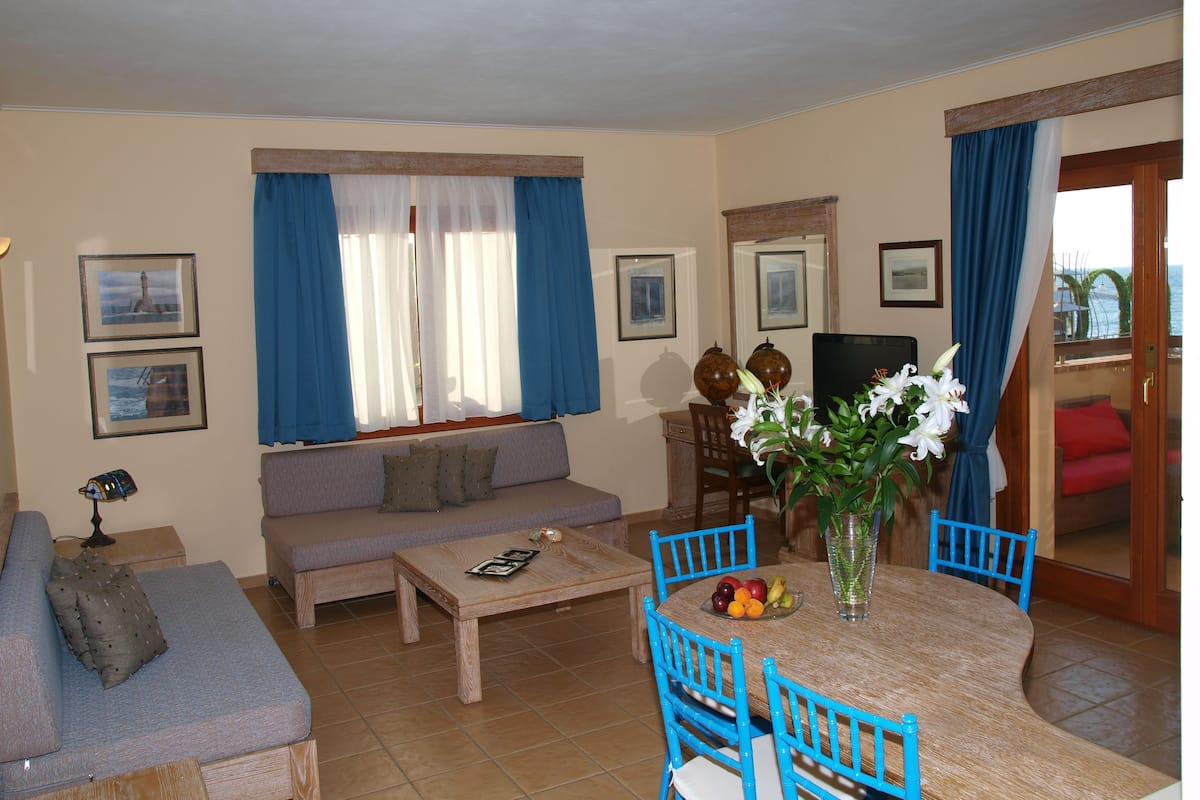 Una sala de estar con sofá, mesa de centro, mesa de comedor con sillas y televisor.