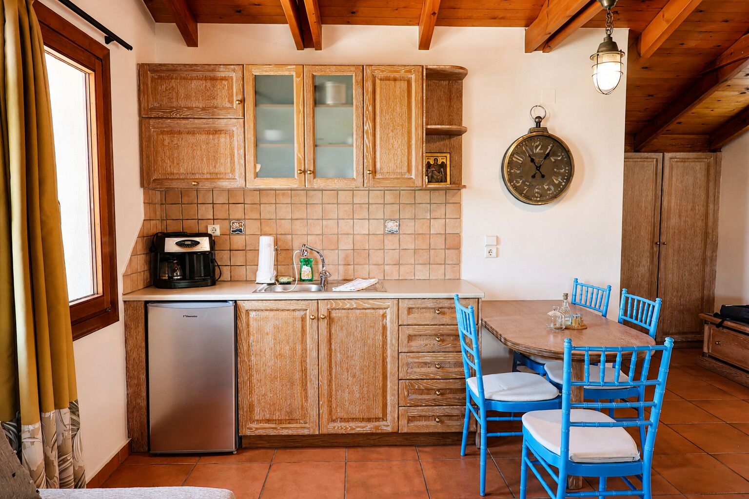 A kitchen with wooden cabinets, a sink, a coffee maker, and a dining table with chairs.