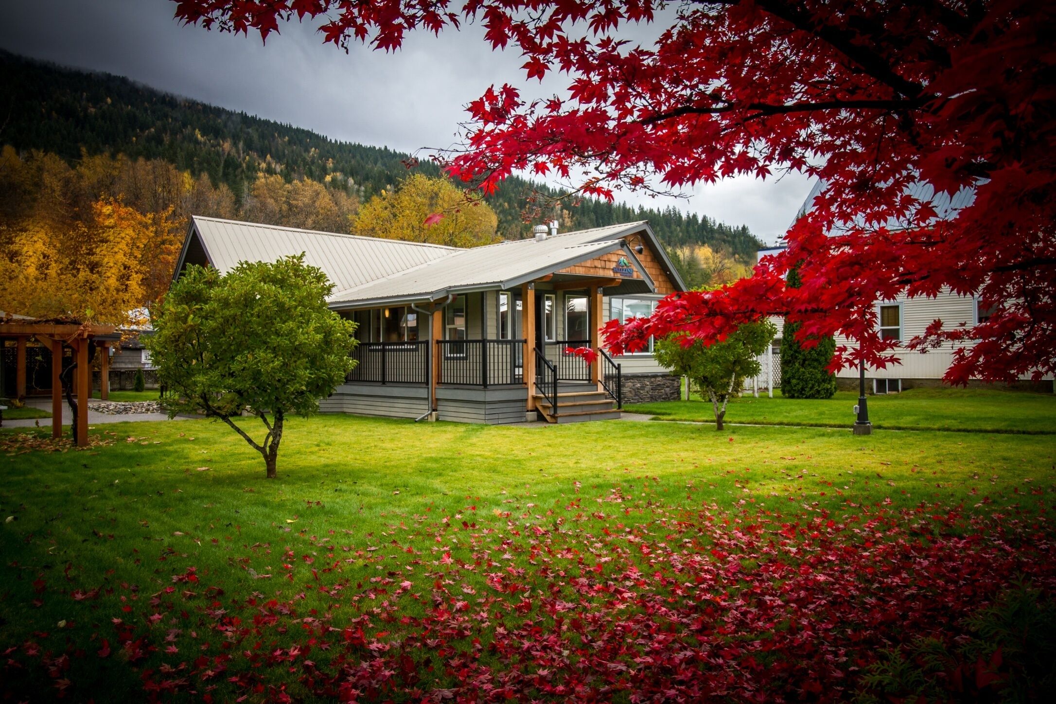 A lodge with a covered porch, a small lawn, and a mountain backdrop.