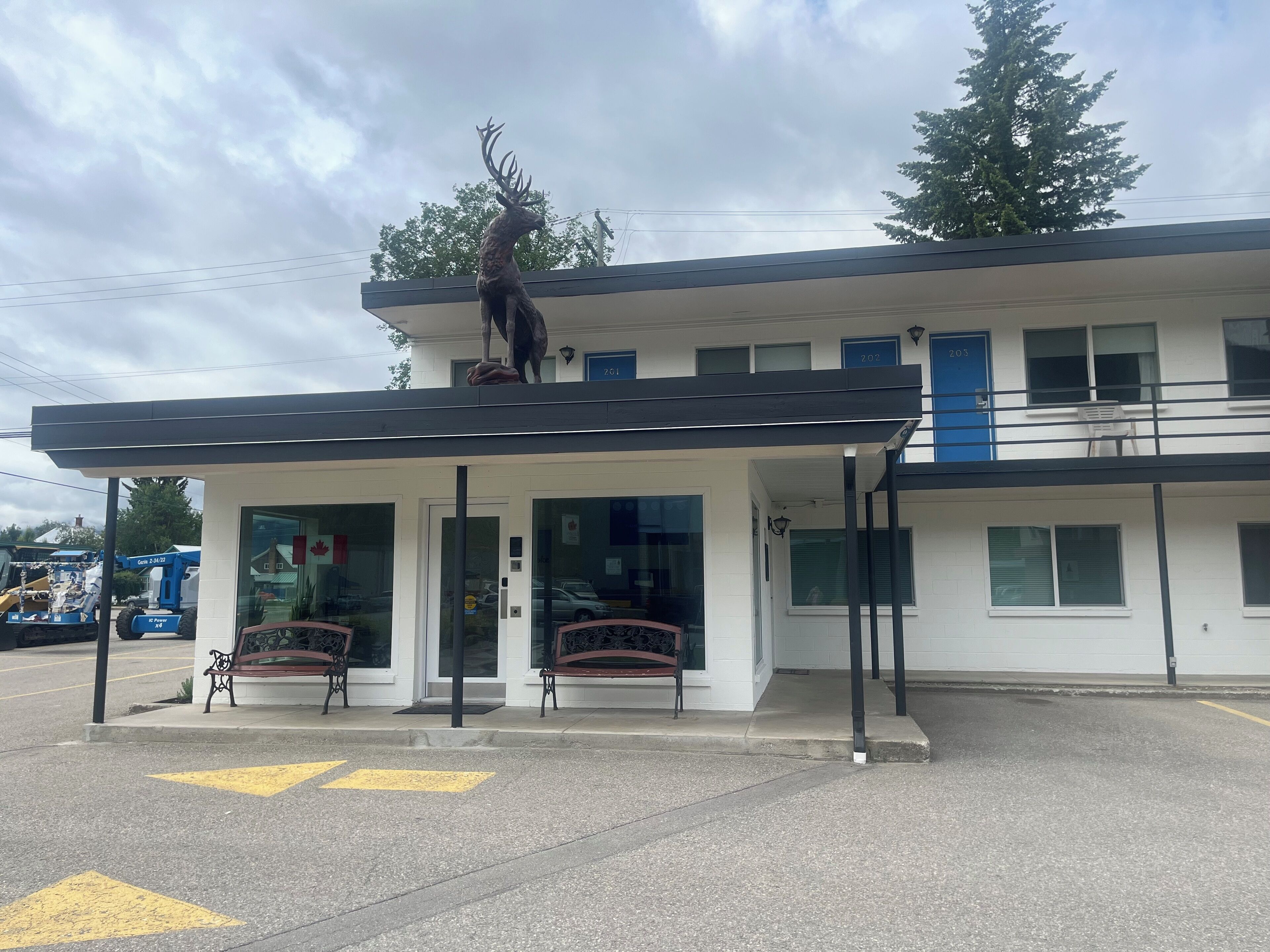 A two-story building with a covered entrance, a large deer sculpture on the roof, and a Canadian flag.