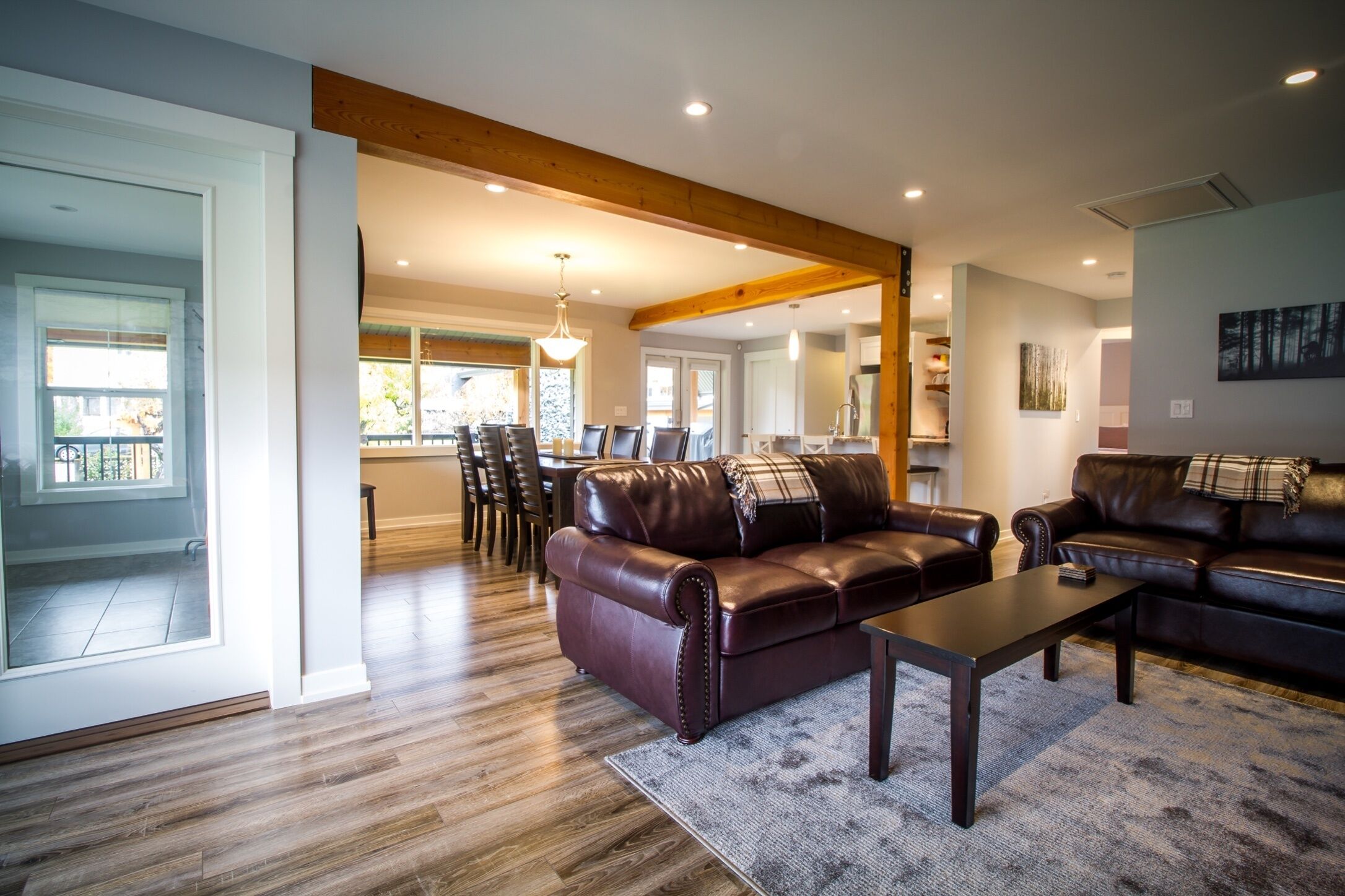 A spacious living room with leather sofas, a coffee table, and a dining area with chairs and a table.