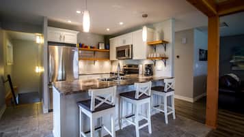 A modern kitchen with white cabinets, stainless steel appliances, and a central island with bar stools.