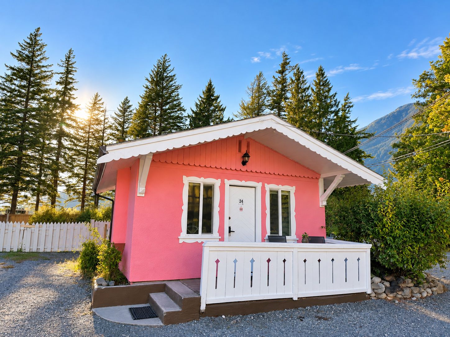 A pink cabin with a white porch, a door, and a window.