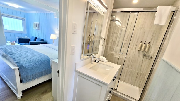 A modern bathroom with a glass shower, a sink, and a mirror. - Richca Chalets Resort (Hope)
