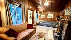 A cozy living room with a wooden ceiling, a fireplace, a sofa, and a coffee table. - Richca Chalets Resort (Hope)