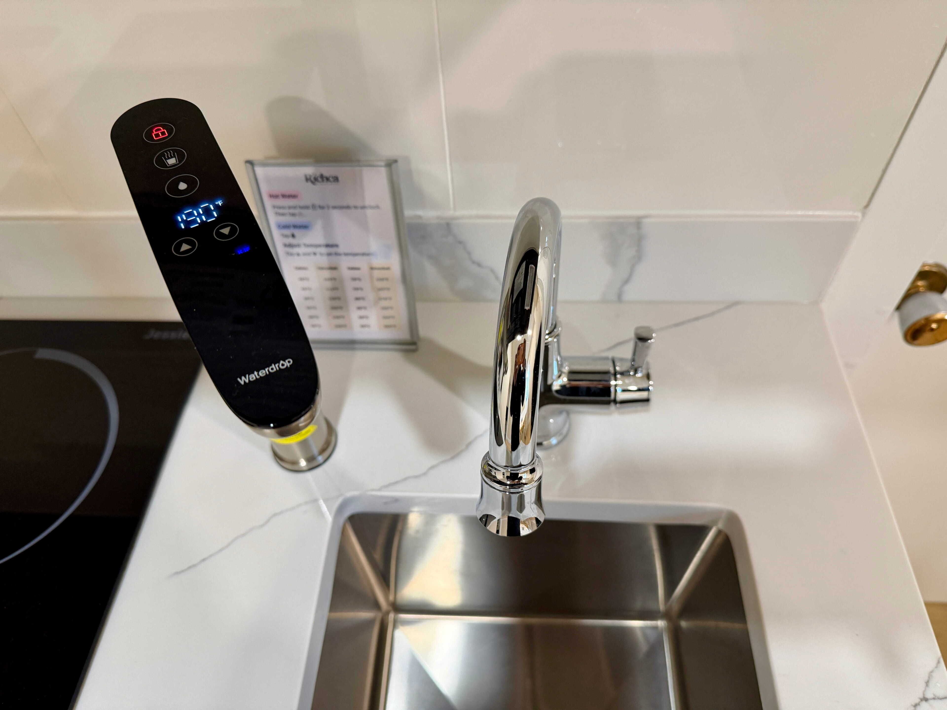 A modern kitchen with a digital faucet, a water temperature control panel, and a stainless steel sink.