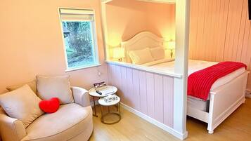 Une chambre à coucher avec un lit, une chaise, une petite table et une fenêtre.
