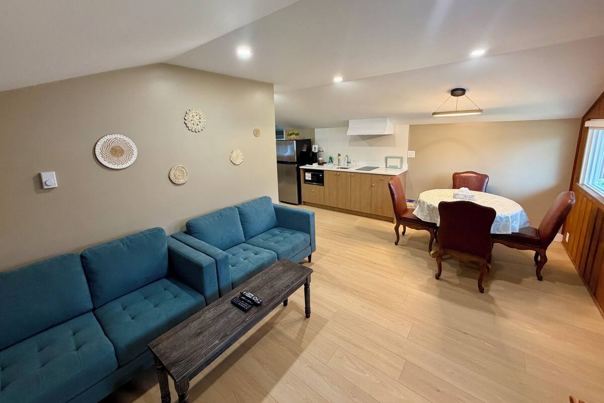 A living room with a blue sofa, a wooden coffee table, and a dining area with a table and chairs.