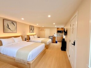 A hotel room with two beds, a kitchenette, a TV, and artwork on the walls. - Richca Chalets Resort (Hope)