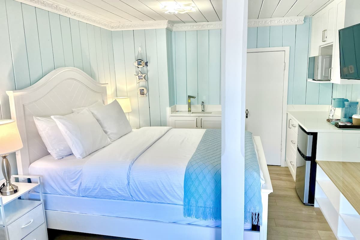 A bedroom with a bed, bedside table, lamp, and a view of the bathroom.