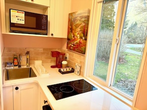 Una cocina moderna con microondas incorporado, cafetera y un amplio ventanal con vistas al exterior.