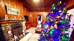 A cozy living room with a fireplace, a Christmas tree, and wooden paneling. - Richca Chalets Resort (Hope)