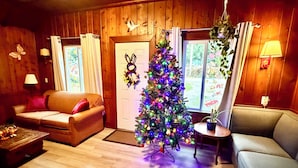 A cozy living room with a wooden interior, a Christmas tree, and two sofas. - Richca Chalets Resort (Hope)