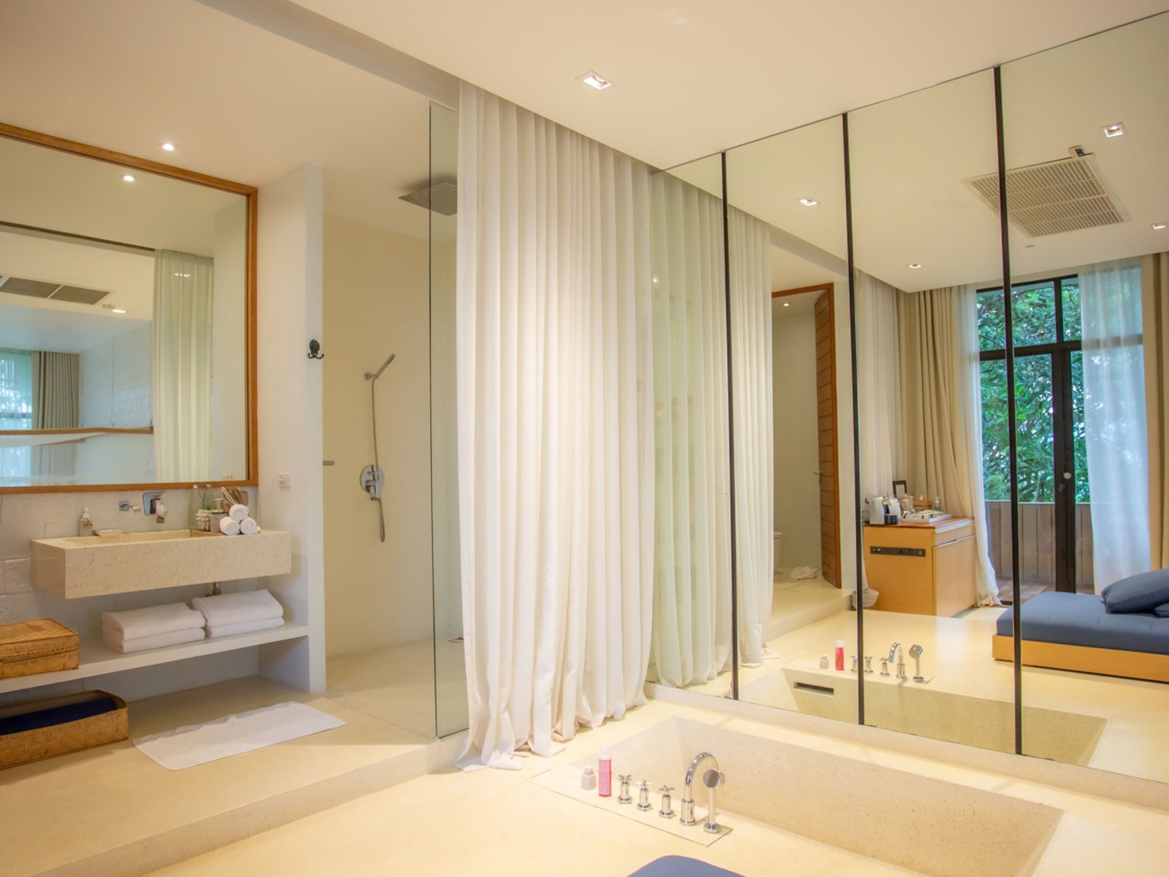 A modern bathroom with a glass shower enclosure, a large mirror, and a built-in sink with a vanity.