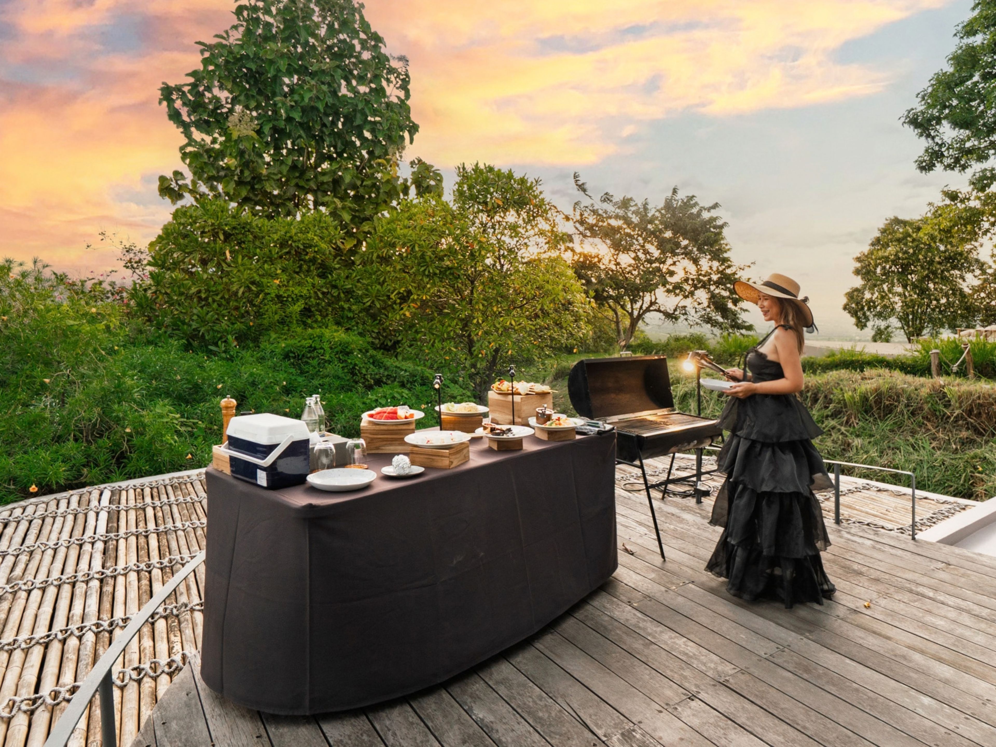 Eine Terrasse mit Grillmöglichkeit, umgeben von Grünflächen und Blick auf den Sonnenuntergang.