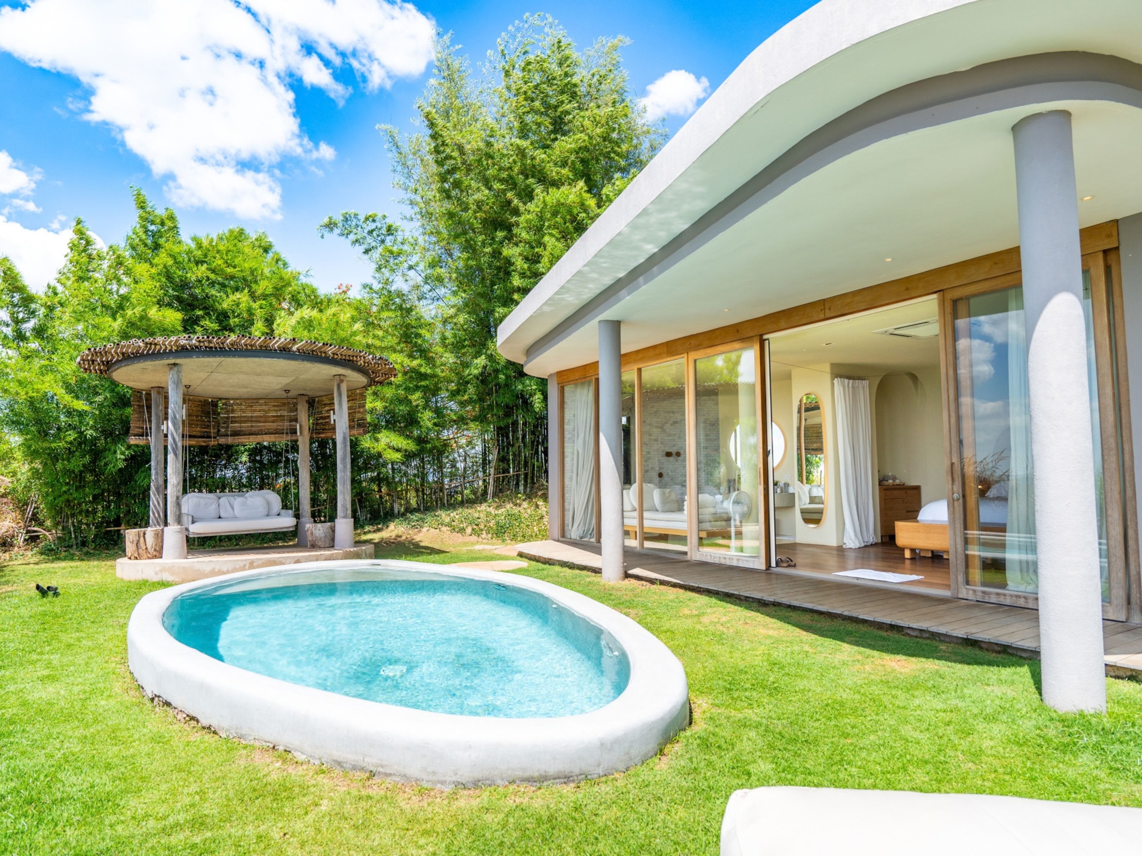 Una casa moderna con piscina, zona de estar exterior techada y un amplio acceso por puerta de cristal.