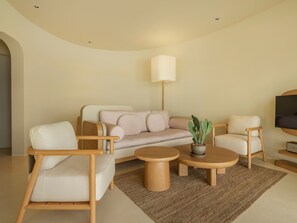 Una sala de estar moderna con un sofá, dos sillones, una mesa de centro y una lámpara de pie.
