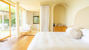 Quarto moderno com uma cama grande, mesa de cabeceira de madeira e vista para o exterior.