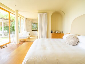 A modern bedroom with a large bed, a wooden nightstand, and a view of the outdoors. - Sala Khaoyai (Pak Chong)