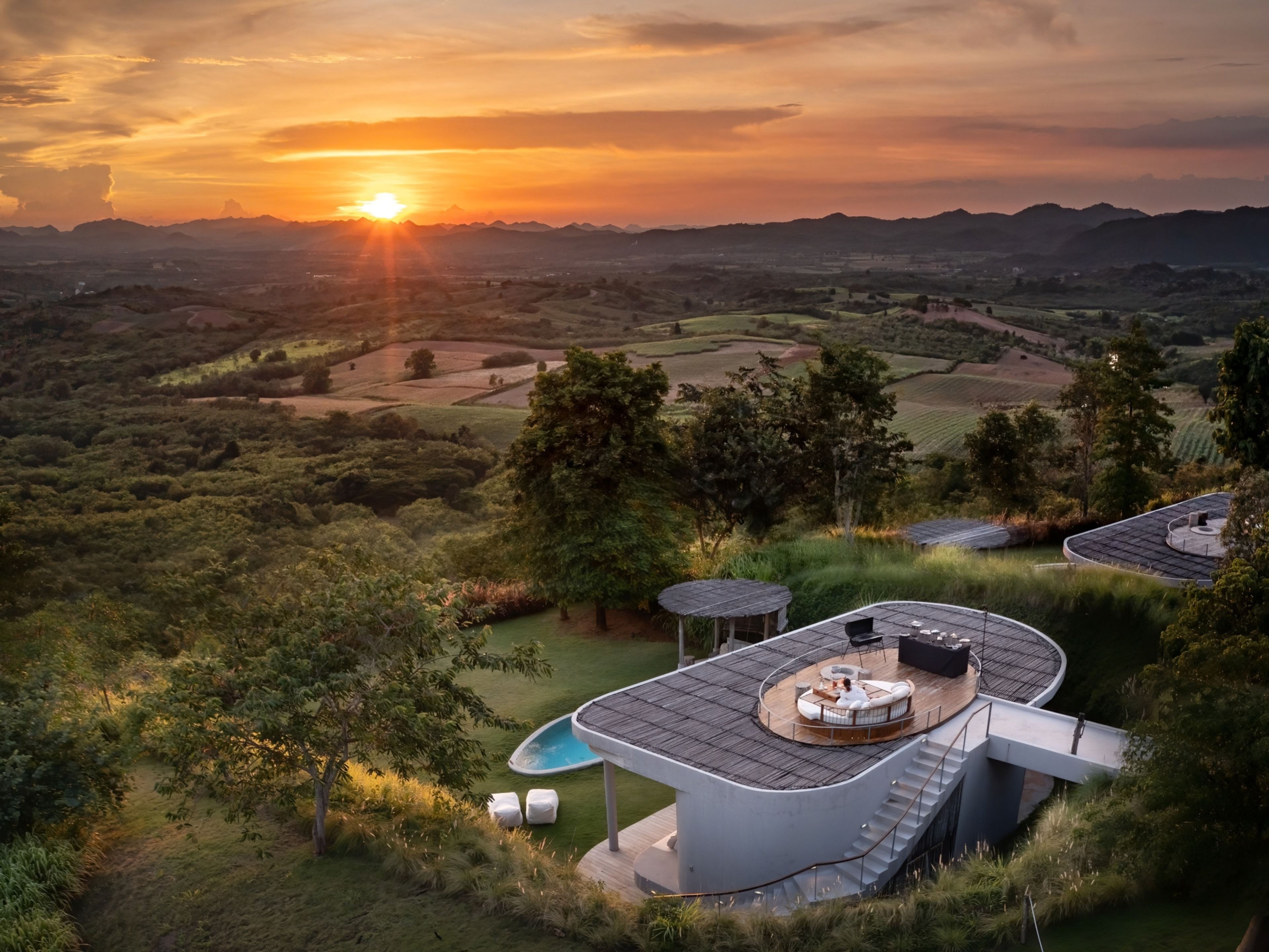 Una villa moderna con piscina, mobiliario exterior y vistas al paisaje circundante.