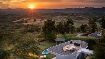 Una villa moderna con piscina, mobiliario exterior y vistas al paisaje circundante.