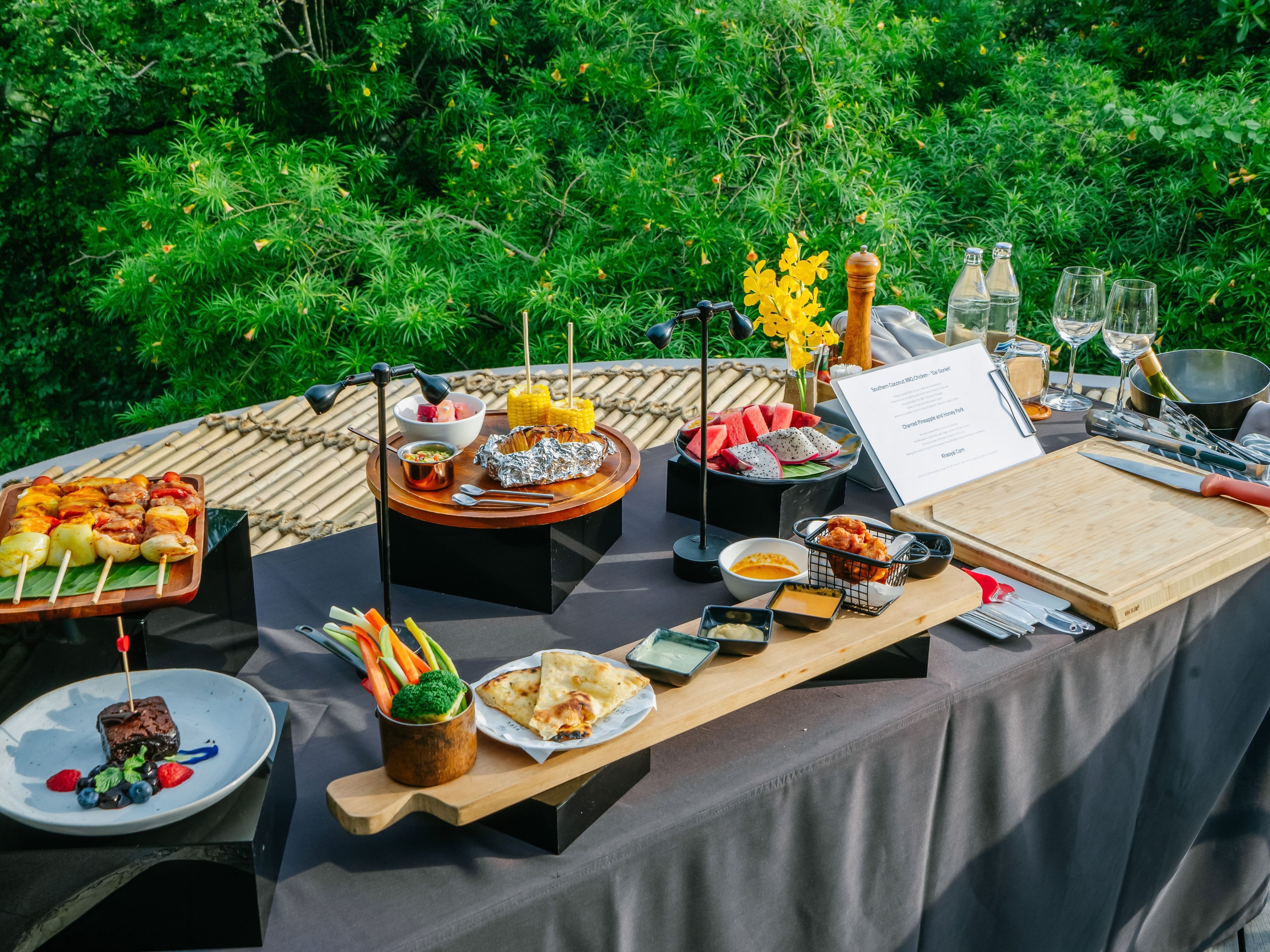 An outdoor dining setup with various food items, a menu, and dining utensils.